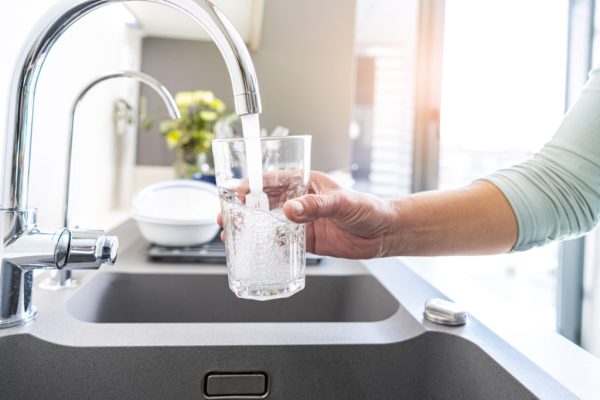 Glass of water being filled in a sink.