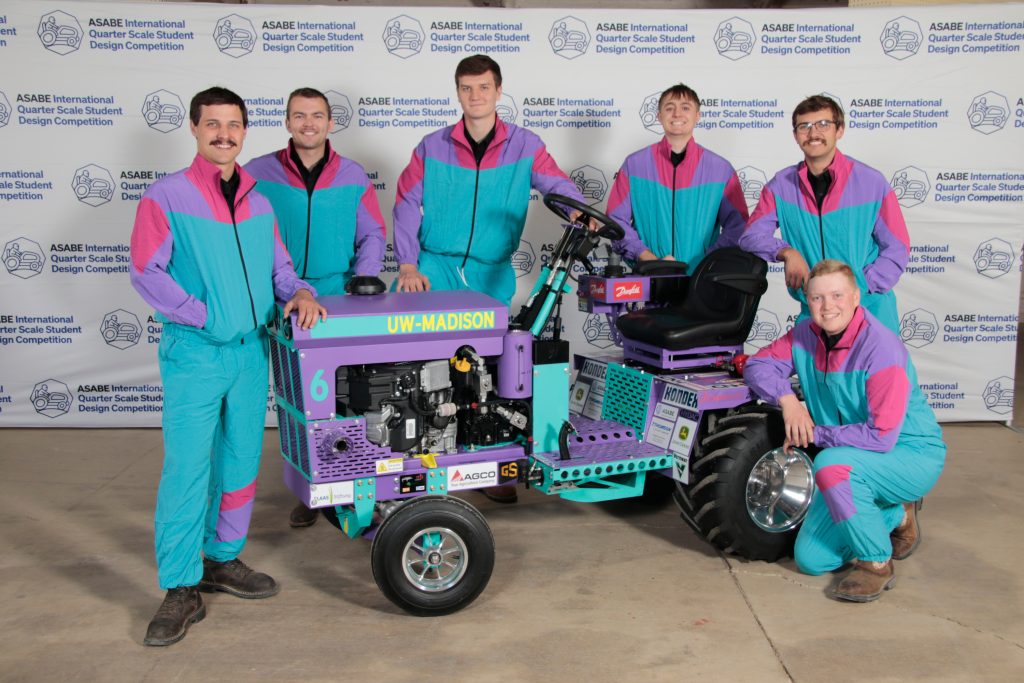 six men stand around tractor