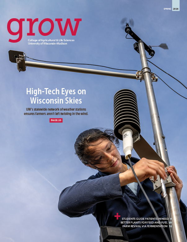 Image of magazine cover with photo of woman working on a piece of equipment against a blue sky with wispy clouds. Text is in red, white and black over the photo.