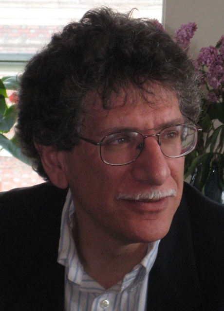 Profile photo of man with brown hair, white mustache and glasses looking off to the side.