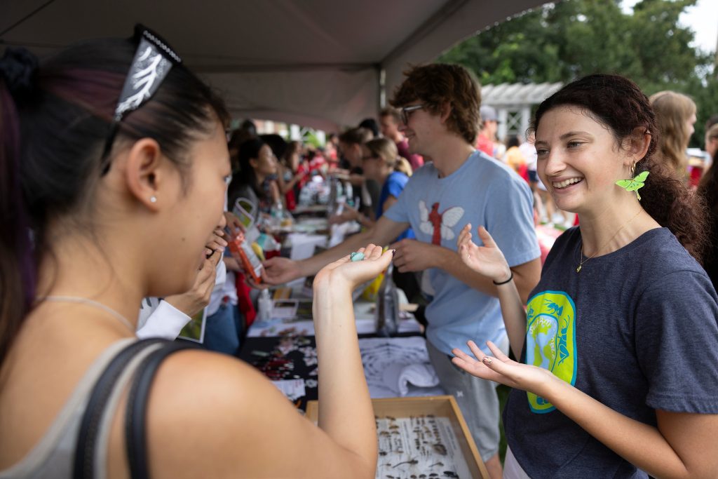 A student holds a hornworm at the entomology major booth