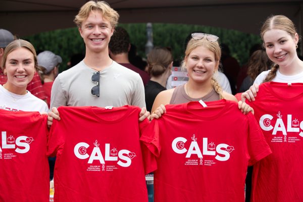 Four students smile holding up CALS shirts