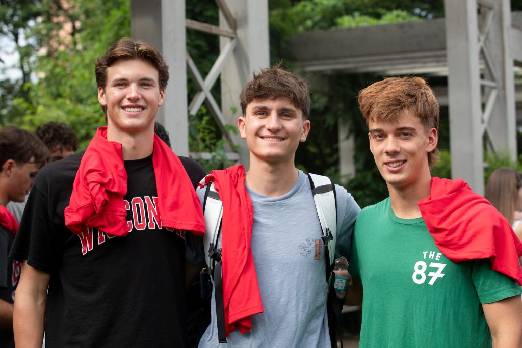A group of three students smile for a photo